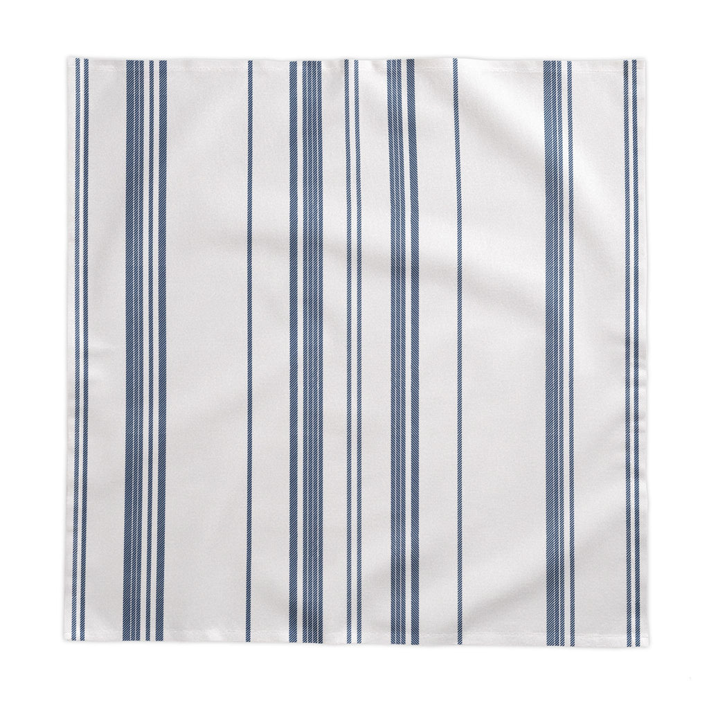 Minimal European dining décor featuring a blue striped tablecloth with white tableware and natural floral arrangements for understated elegance.