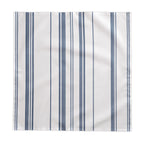Minimal European dining décor featuring a blue striped tablecloth with white tableware and natural floral arrangements for understated elegance.