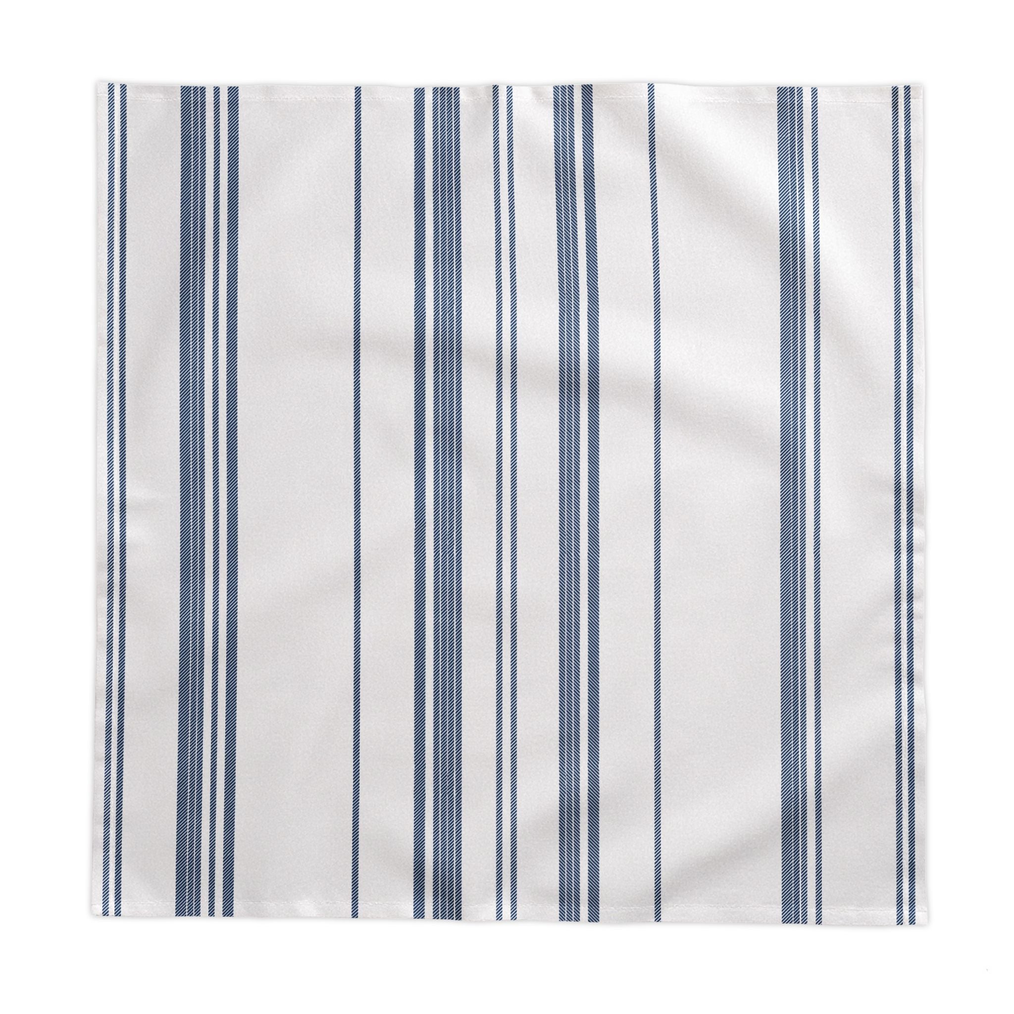 Minimal European dining décor featuring a blue striped tablecloth with white tableware and natural floral arrangements for understated elegance.