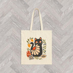 Eco-friendly canvas tote with whimsical black cat design, olive branches, lemons, and Mediterranean pottery accents.