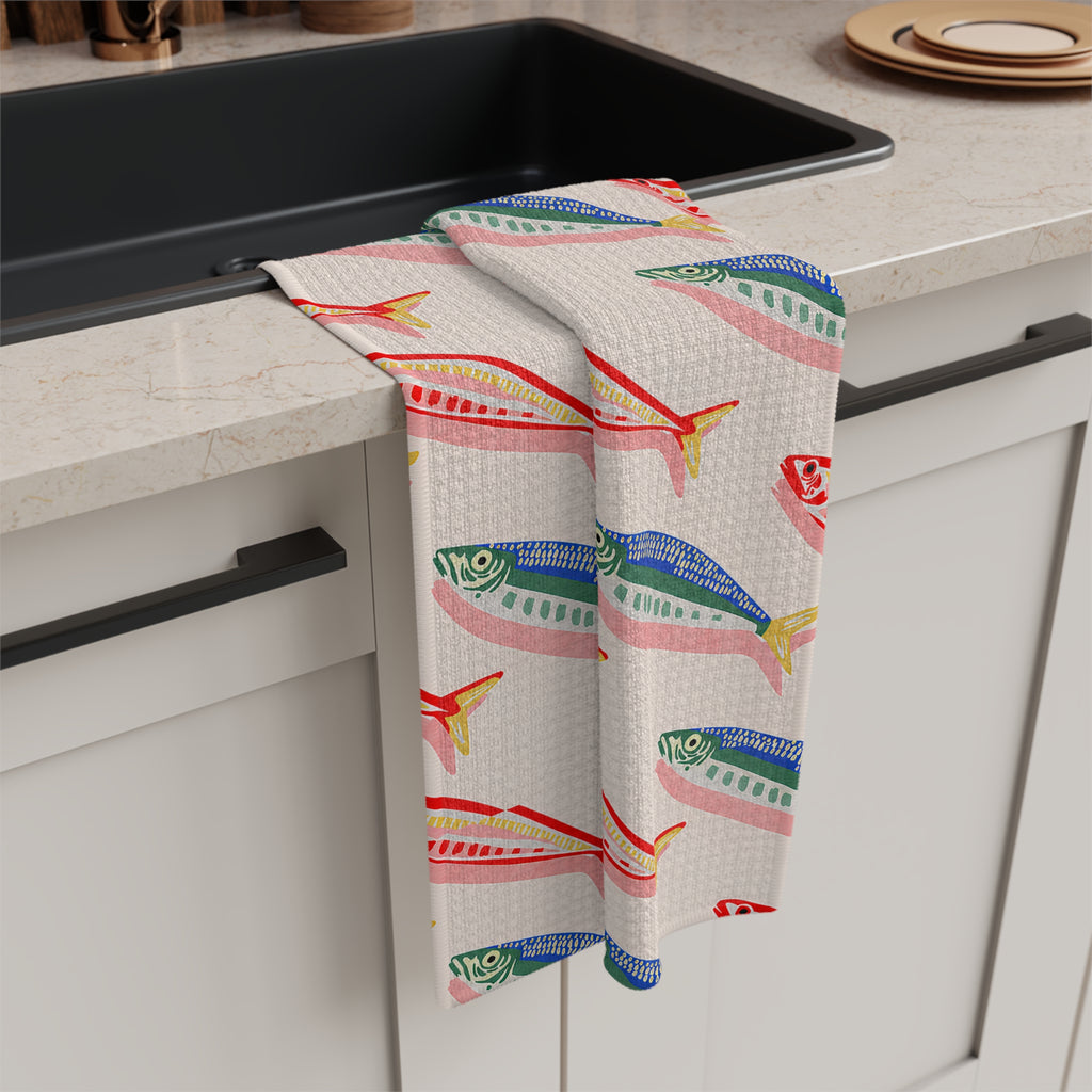 Mediterranean coastal tea towel design featuring rows of colourful fish on a neutral background for elegant kitchen styling.