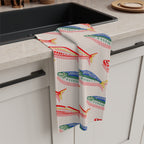 Mediterranean coastal tea towel design featuring rows of colourful fish on a neutral background for elegant kitchen styling.