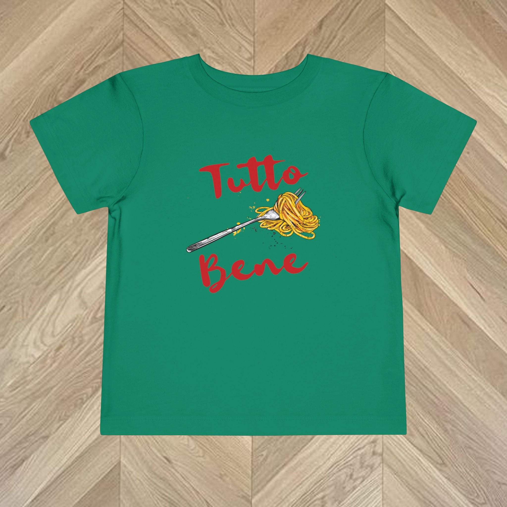 Kelly green kids “Tutto Bene” pasta graphic t-shirt featuring a spaghetti fork illustration with bold red Italian lettering, playful Italian food themed tee for toddlers and youth.
