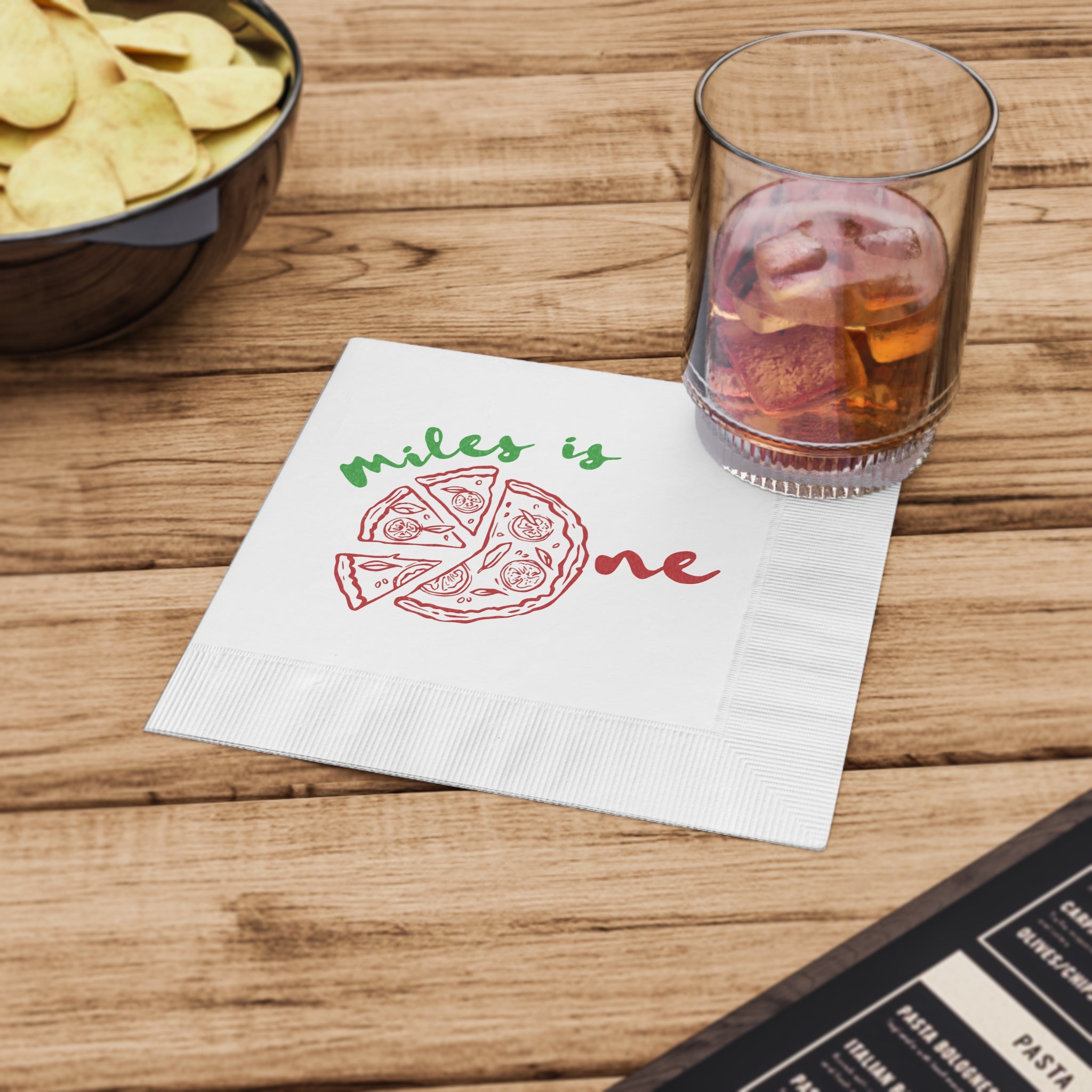 Custom kids' birthday napkin with a fun pizza illustration, personalized for a first birthday celebration and party table.