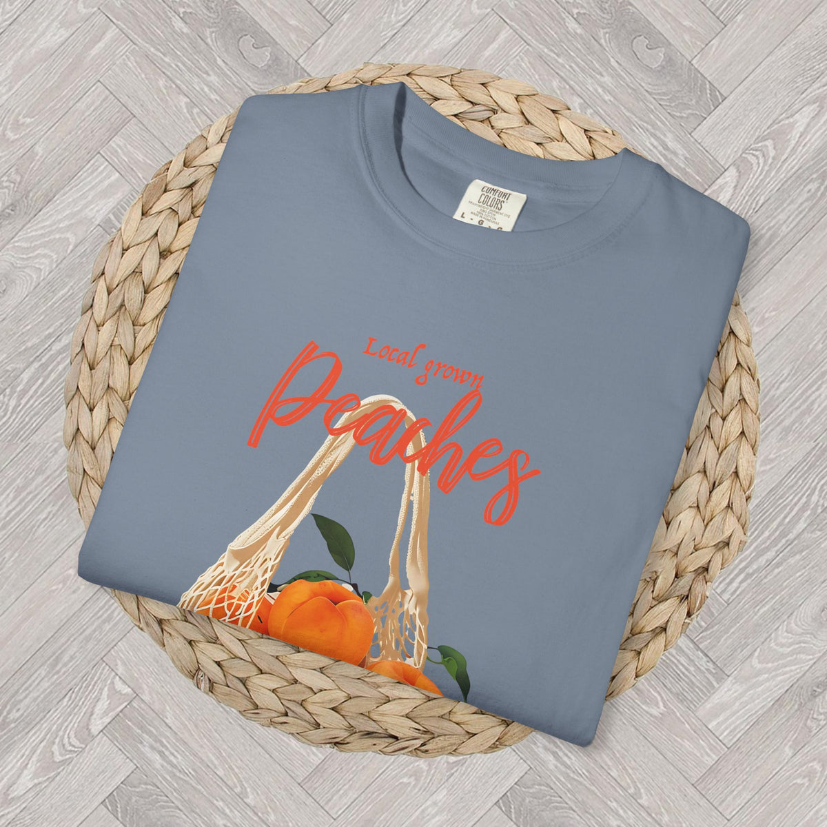 Close-up of the Farm Fresh Peaches T-shirt graphic showing a produce bag filled with ripe peaches, green leaves, and vintage-style “Local Grown” and “Farm Fresh” lettering.