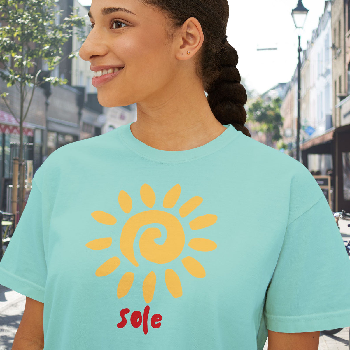 Detail shot: Close-up of the SOLE T-shirt showing the warm golden sun illustration, hand-lettered typography and soft garment-dyed cotton texture.