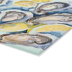 Close-up view of watercolor oyster shells and fresh lemon slices design on a decorative glass cutting board
