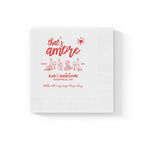 Personalized bridal shower napkin with That's Amore design, custom bride's name, location, and event date printed in red.