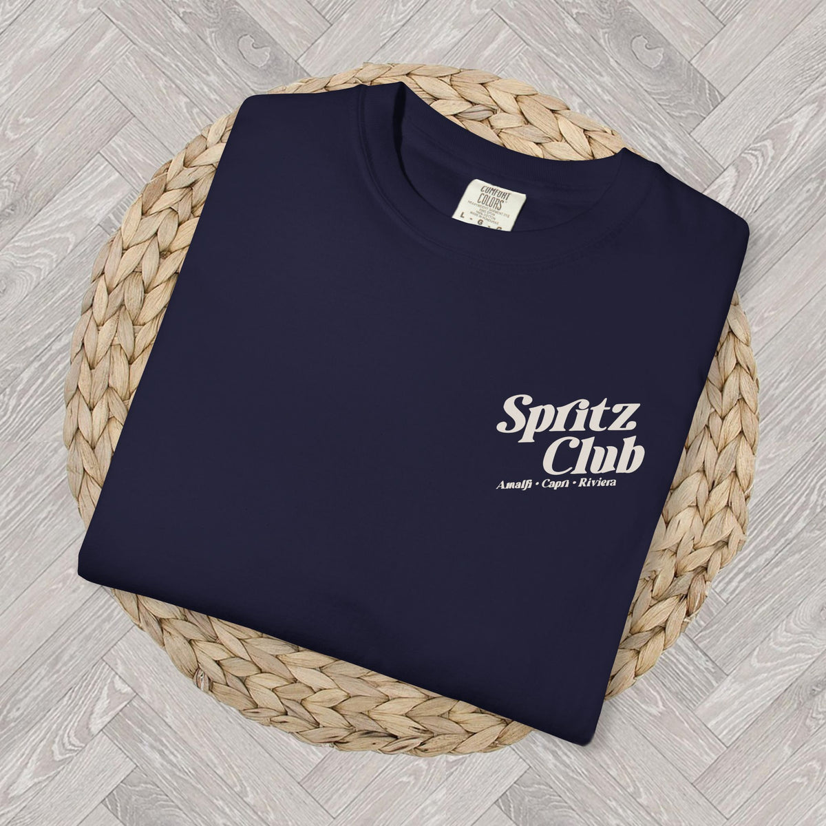 Close-up folded Spritz Club T-shirt displaying the minimalist front chest text detail and relaxed Mediterranean lifestyle aesthetic