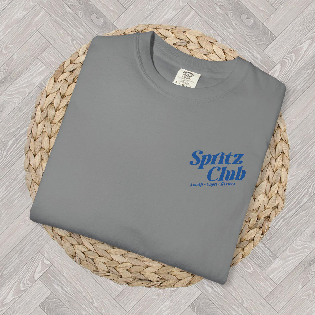 Close-up of folded Spritz Club T-shirt showing small front left-chest text design with Mediterranean-inspired branding
