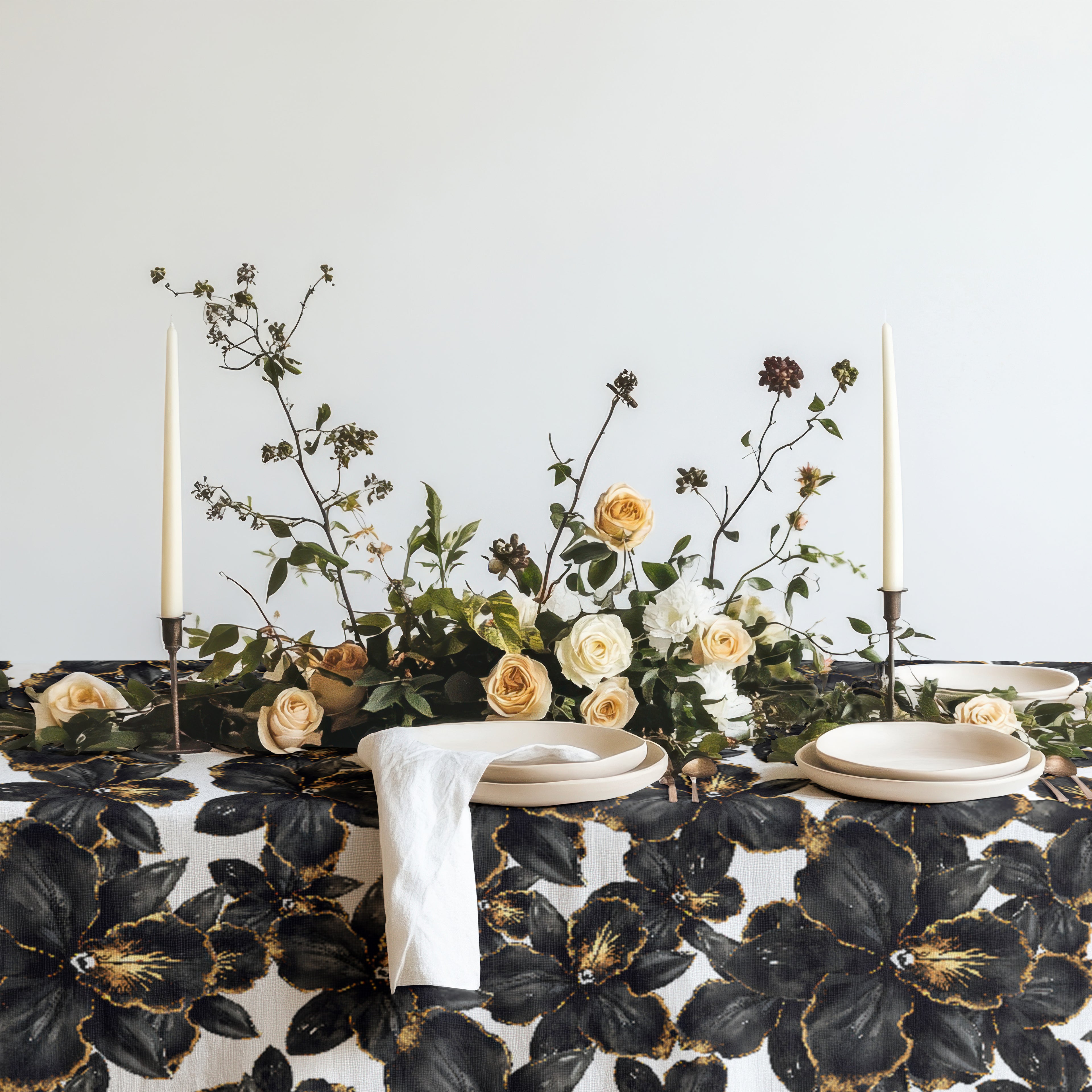 Black orchid botanical tablecloth styled on a dining table with neutral ceramic plates and floral centrepiece, modern luxury table linen in black and ivory