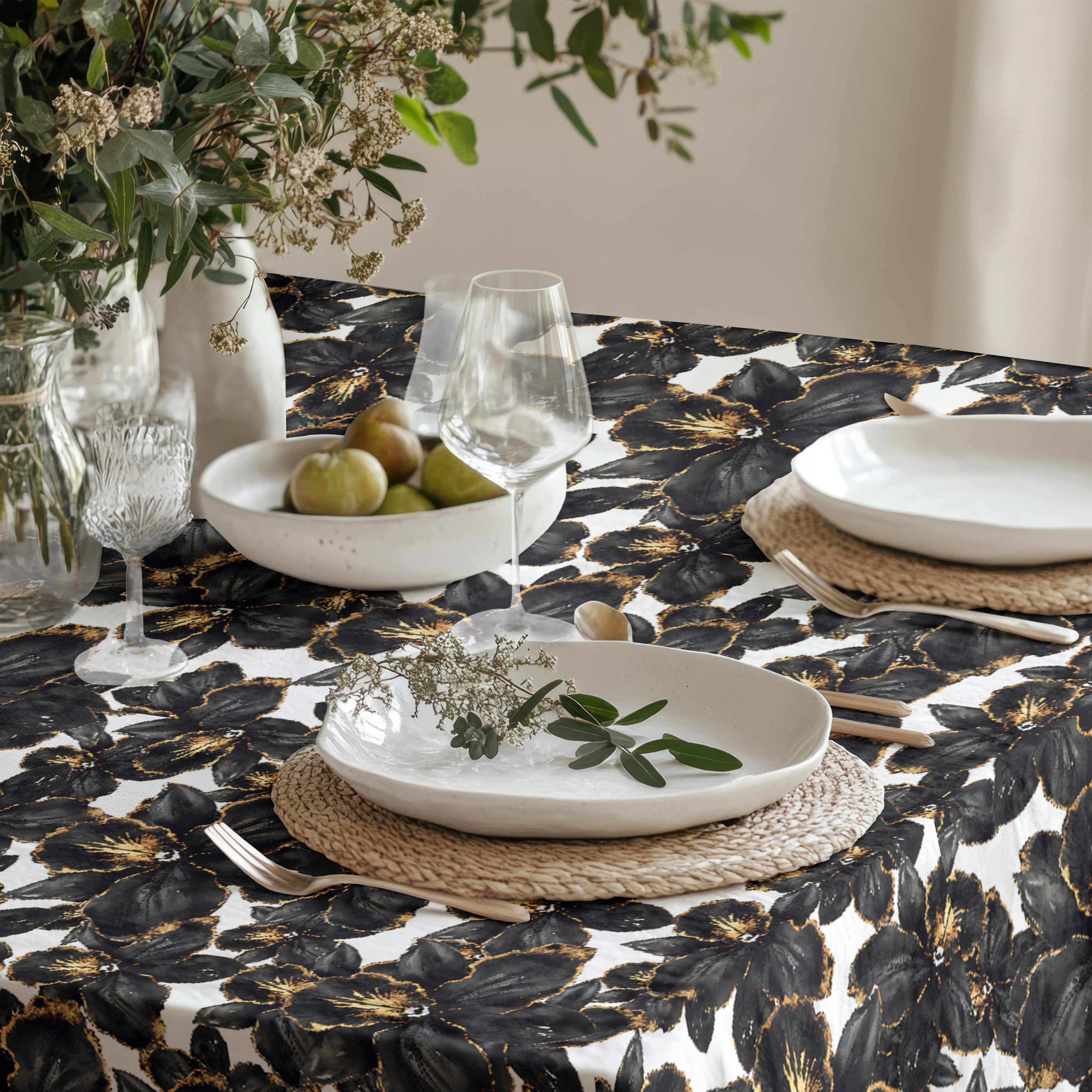 Close-up of black orchid floral pattern on botanical tablecloth, showing textured fabric and gold-accented detailing on an ivory base