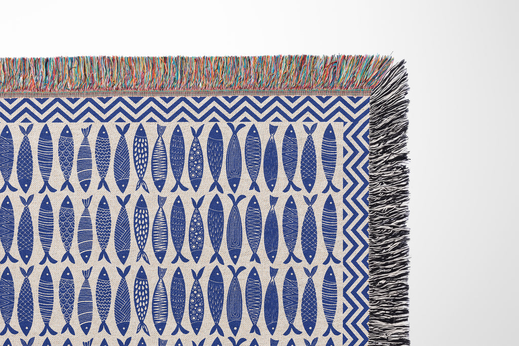 Close-up view of woven thread texture and colorful fringe detailing on a nautical cotton blanket