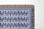 Close-up view of woven thread texture and colorful fringe detailing on a nautical cotton blanket