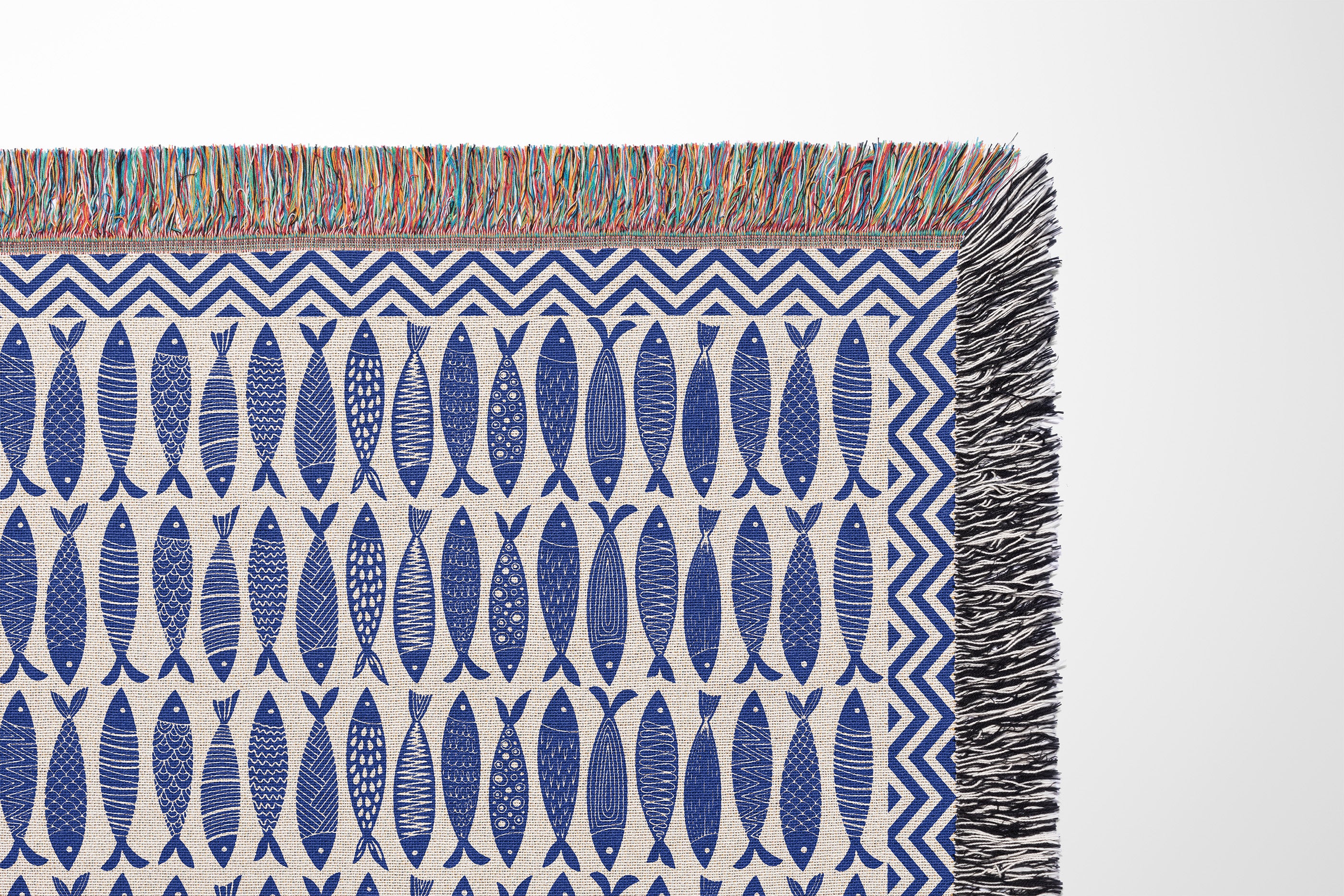 Close-up view of woven thread texture and colorful fringe detailing on a nautical cotton blanket