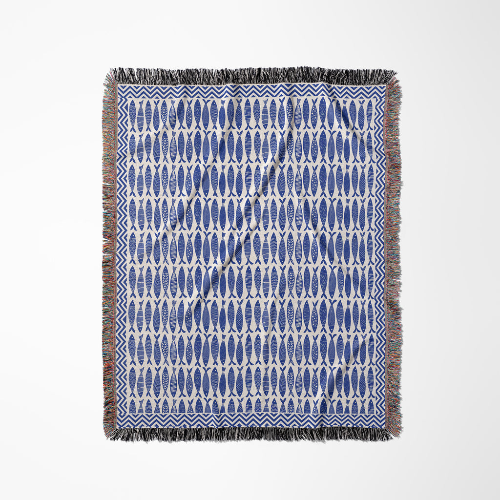 Ocean-inspired woven blanket with repeating blue fish motifs for coastal, boho, and seaside interiors