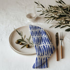 Blue fish coastal cotton twill cloth napkin displayed on dining table with nautical ocean-inspired decor