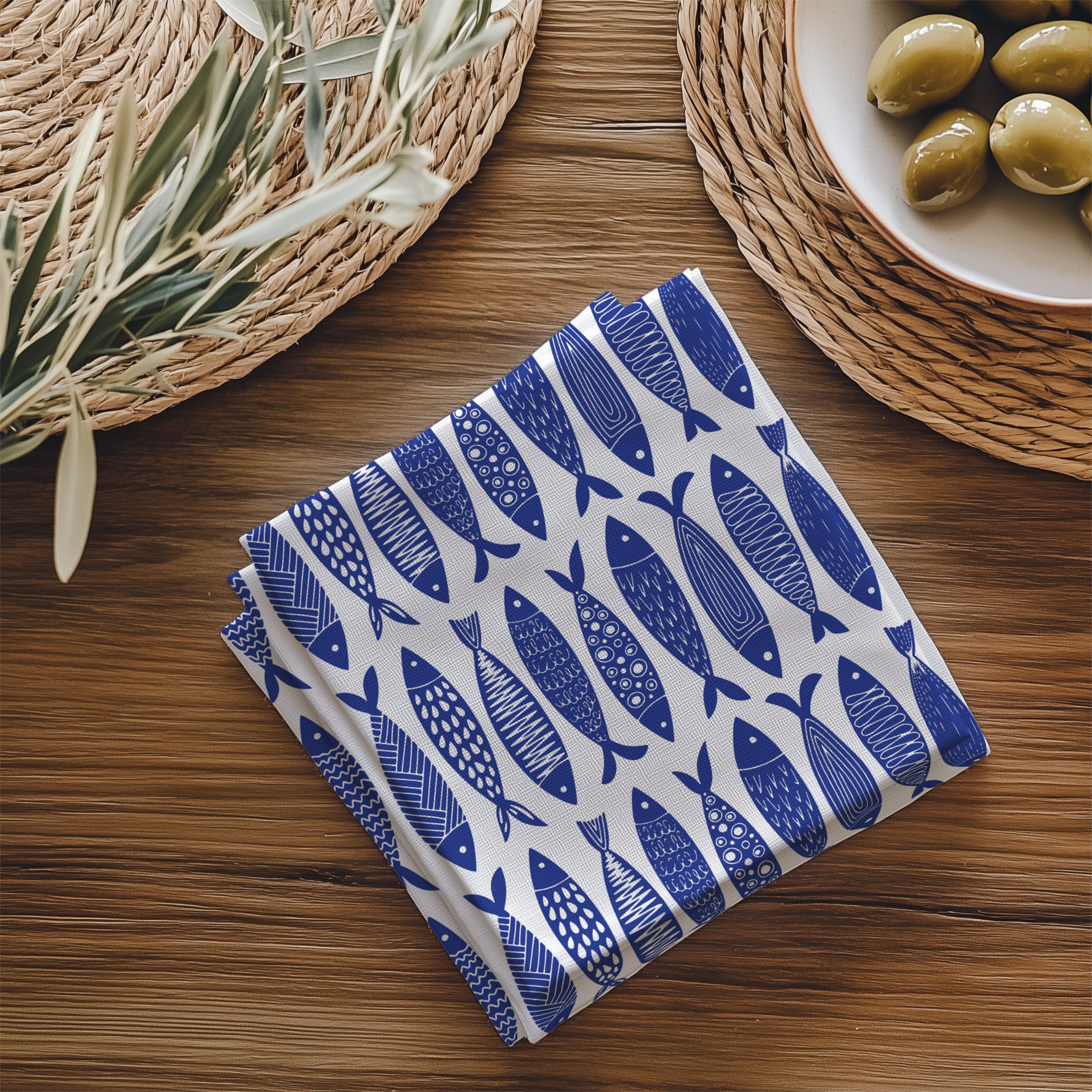 Close-up view of blue fish patterned cotton napkin showing detailed coastal print and soft twill fabric texture