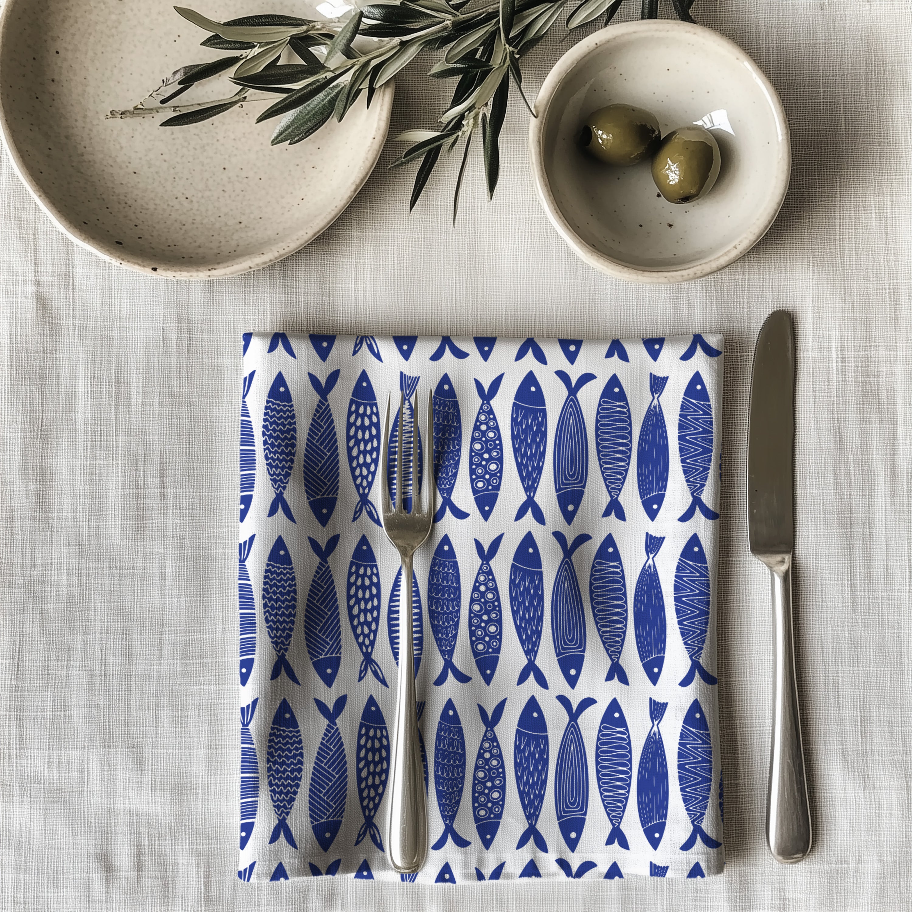 Single blue fish dinner napkin folded on table showcasing one-sided ocean pattern print and premium reusable cotton fabric