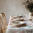Modern Mediterranean table setting with colourful Cin Cin Italian aperitivo tablecloth, ceramic plates, flowers and relaxed dining decor