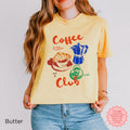 A butter yellow Coffee Club crop top with an illustration of a croissant, moka pot, and coffee cup, perfect for coffee lovers.