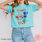 Trendy chalky mint crop top with a retro coffee design, featuring a coffee cup, moka pot, and croissant in vibrant colors.