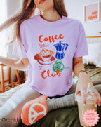 Orchid-colored Coffee Club crop top with a colorful graphic of a coffee cup, moka pot, and croissant, perfect for everyday wear.