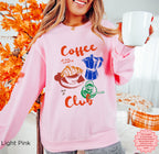 Light pink Coffee Club sweatshirt with a fun coffee graphic, showcasing a croissant, espresso machine, and coffee cup. Perfect for relaxed weekends.