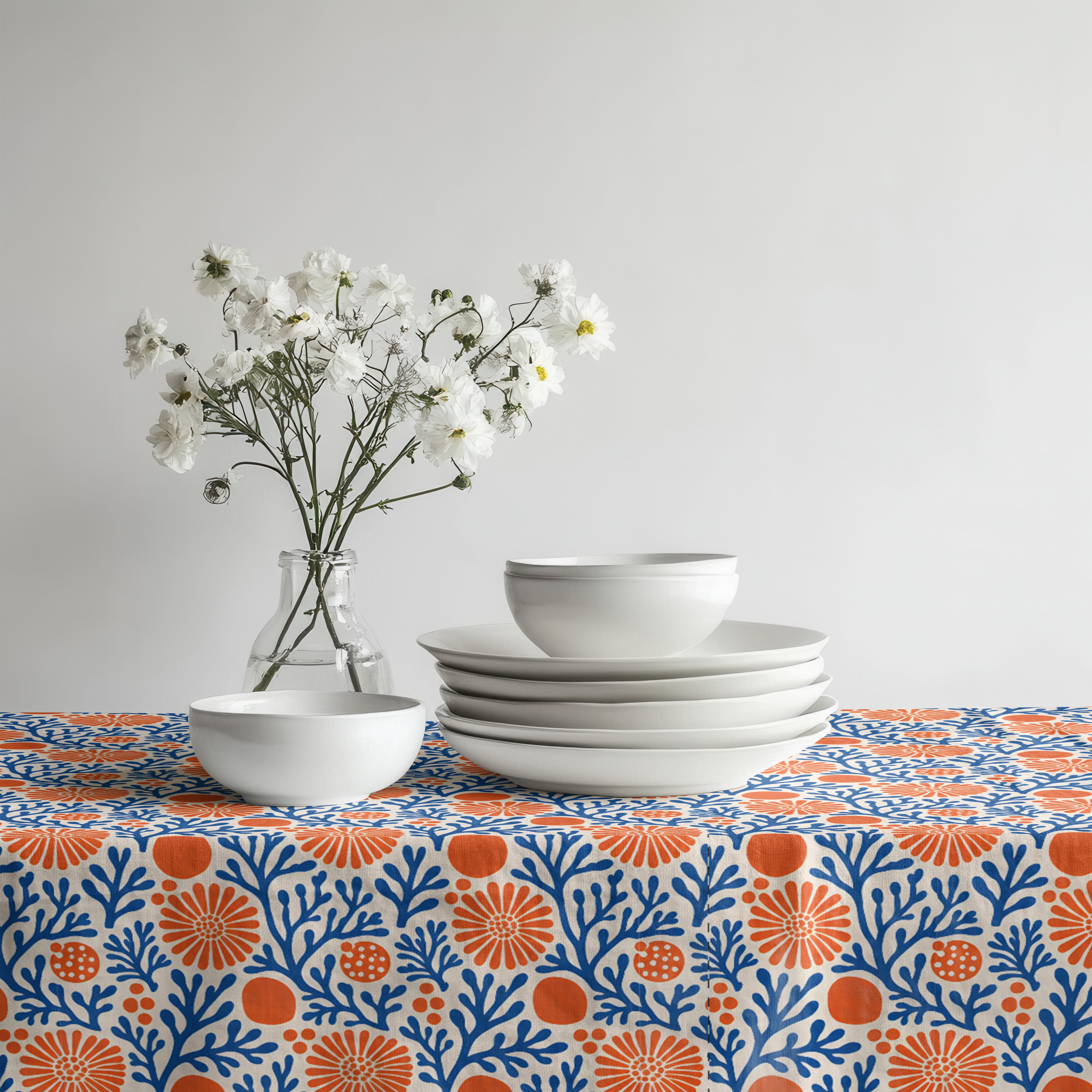 Mediterranean Coral Reef Tablecloth featuring cobalt blue coral branches and terracotta florals styled with white ceramic dinnerware.