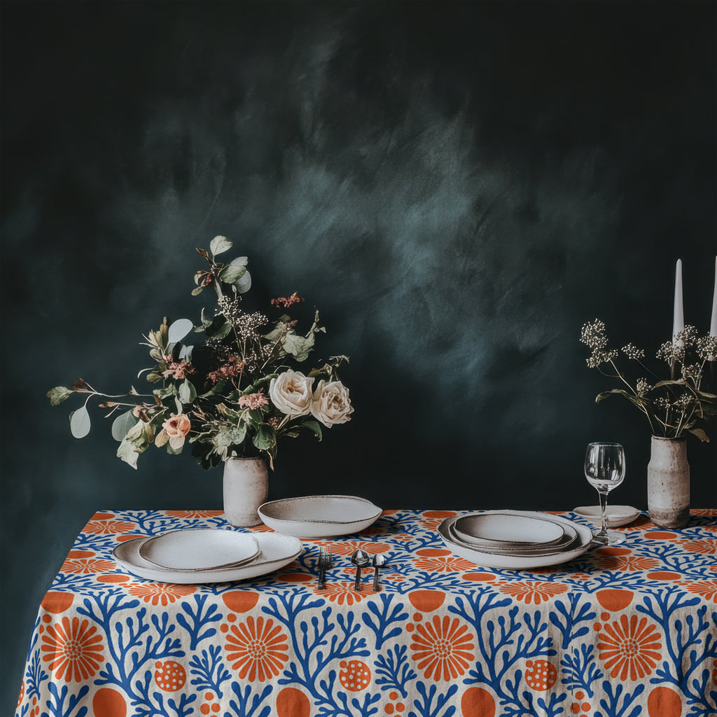 Mediterranean coral pattern tablecloth styled with white plates, glassware, and fresh flowers for coastal entertaining.