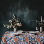 Mediterranean coral pattern tablecloth styled with white plates, glassware, and fresh flowers for coastal entertaining.