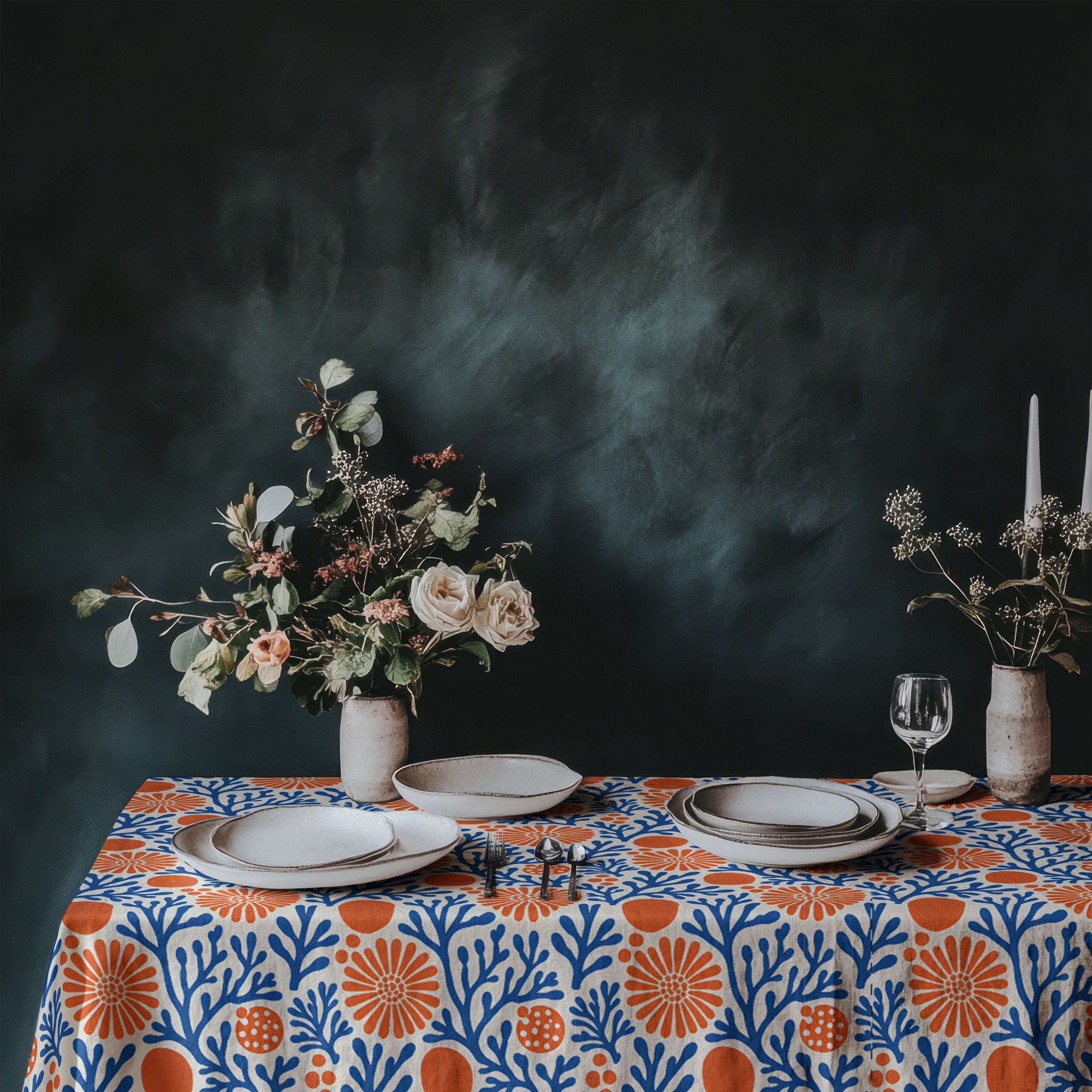 Mediterranean coral pattern tablecloth styled with white plates, glassware, and fresh flowers for coastal entertaining.