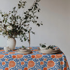 Mediterranean coastal tablecloth styled for everyday dining with white dinnerware and fresh seasonal flowers.