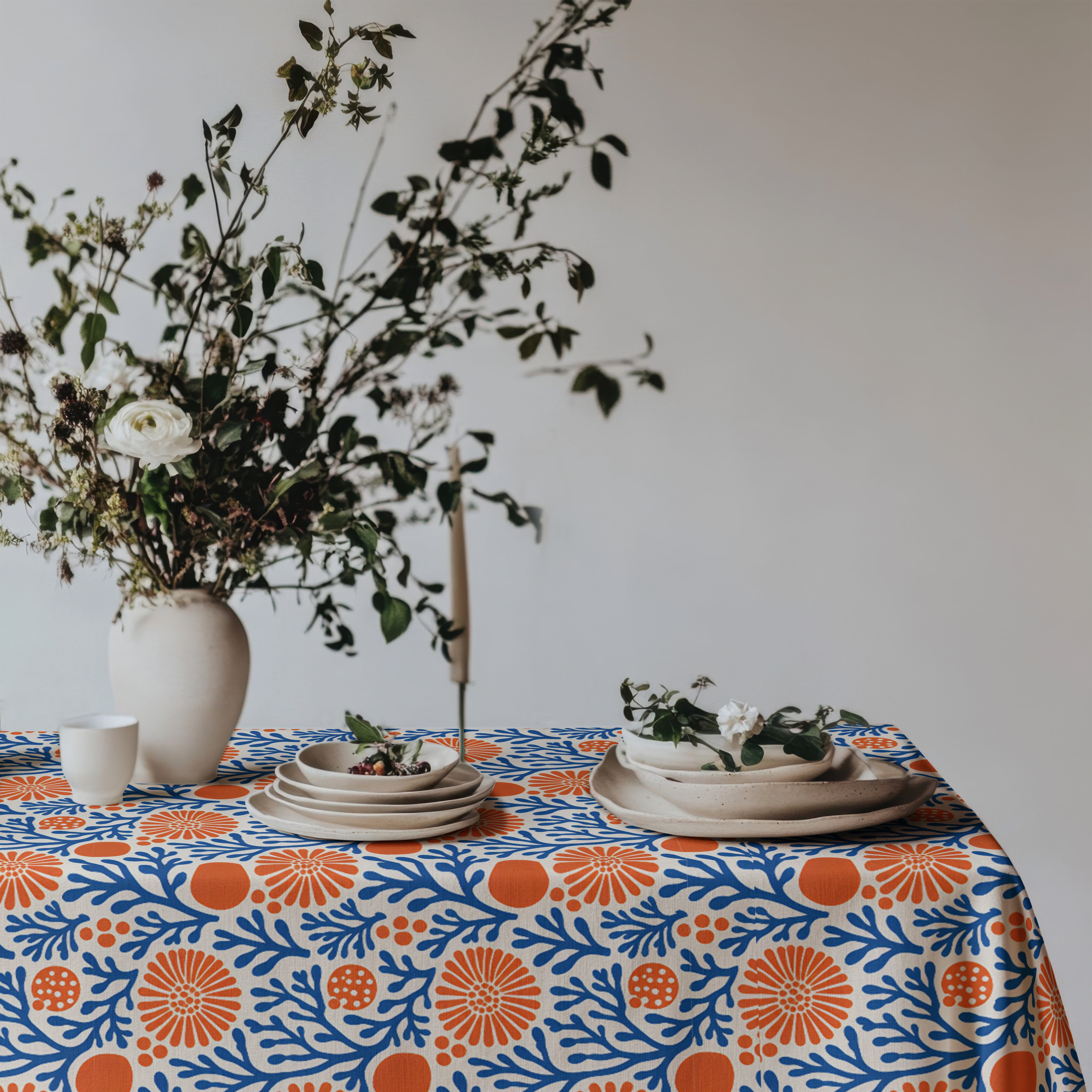 Mediterranean coastal tablecloth styled for everyday dining with white dinnerware and fresh seasonal flowers.