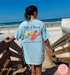 Light blue Cote d’Azur summer vacation t-shirt with coastal watercolor lobster and oyster graphic, worn at the beach, ideal for seafood enthusiasts and French Riviera lovers.