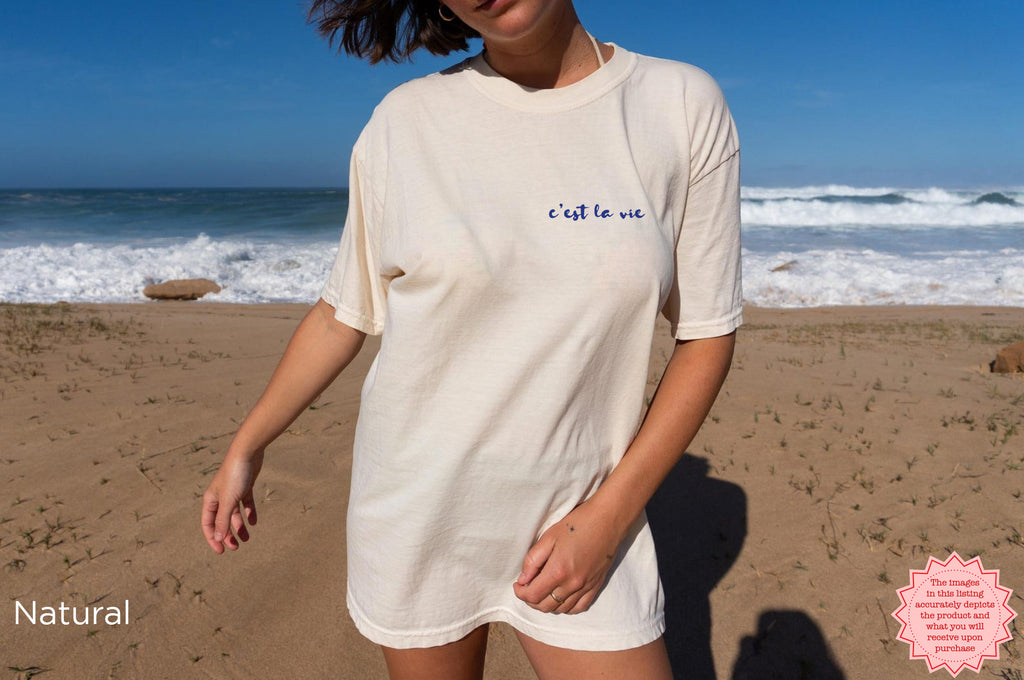 Natural-colored Cote d’Azur t-shirt with watercolor lobster, oysters, and lemons graphic, casual coastal style, worn at home, celebrating lobster roll lovers and seaside vacation vibes.