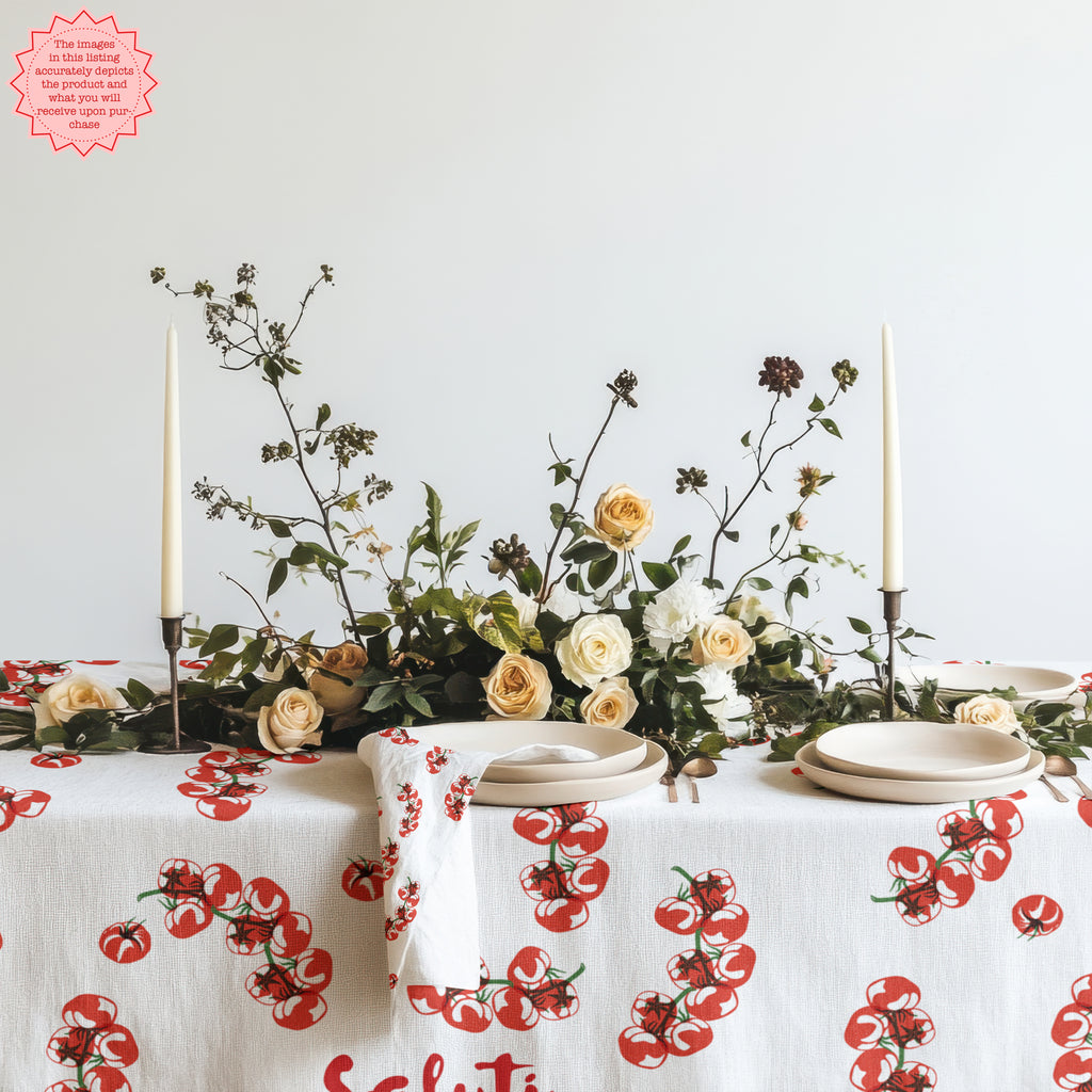 Mediterranean-inspired Tomato Block Print Tablecloth on a dining table with neutral plates and a vase of flowers. The vibrant tomato design adds a colorful and fresh touch to the table setting.