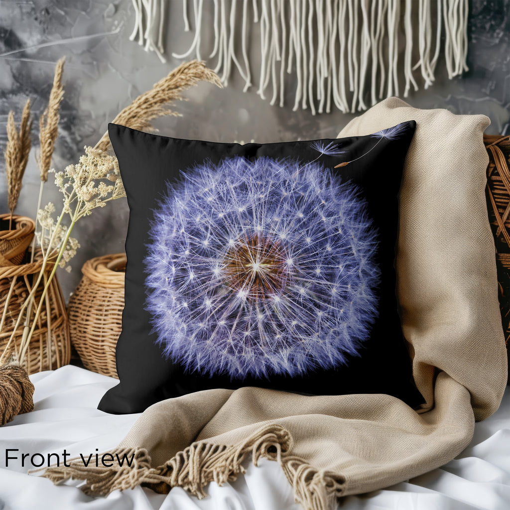 Front view of the Detailed Dandelion Cushion showcasing the intricate dandelion design on a black background. The cushion is placed on a cozy bed with a beige throw and soft woven textures.