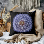 Front view of the Detailed Dandelion Cushion showcasing the intricate dandelion design on a black background. The cushion is placed on a cozy bed with a beige throw and soft woven textures.