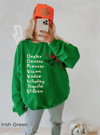 Woman wearing a funny Christmas cocktail sweatshirt with festive lettering, styled with light denim shorts in a cosy holiday setting.