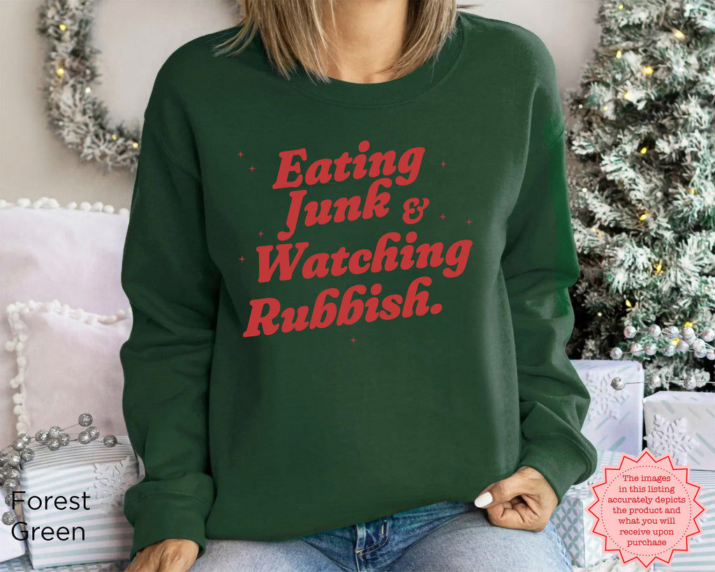 Christmas sweatshirt styled with snacks and a cosy movie-night setting, featuring humorous retro holiday lettering.