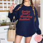 Festive crewneck sweatshirt featuring a vintage-style Christmas movie night design and “Eating Junk & Watching Rubbish” text.