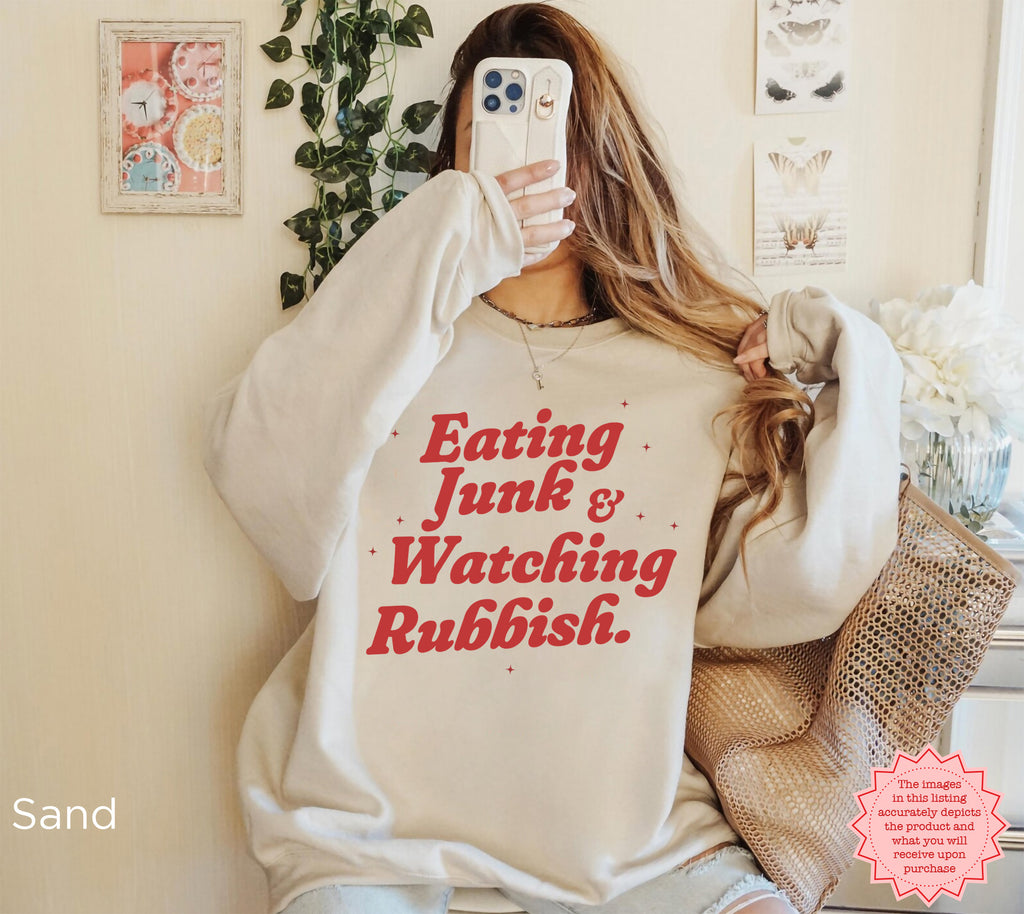 Close-up of a funny Christmas crewneck sweatshirt featuring retro-inspired “Eating Junk & Watching Rubbish” lettering.