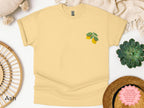 Close-up of folded Gildan 5000 t-shirt with embroidered lemon and botanical details