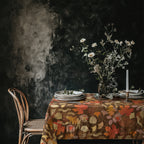 Rustic fall dining table decorated with an autumn leaf tablecloth, ceramic dinnerware, and natural centerpiece