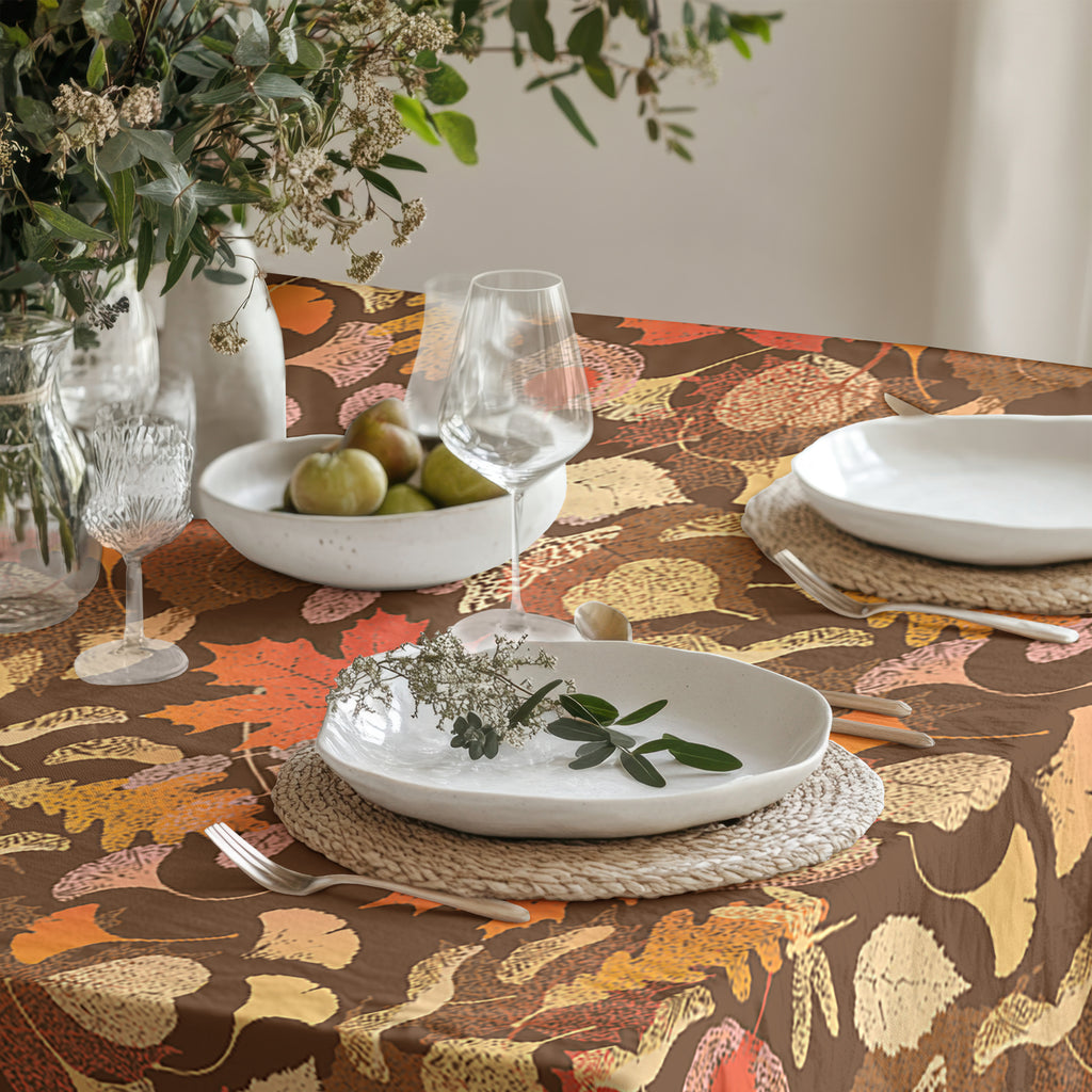 Elegant Thanksgiving table setting with fall leaf print tablecloth and neutral ceramic tableware