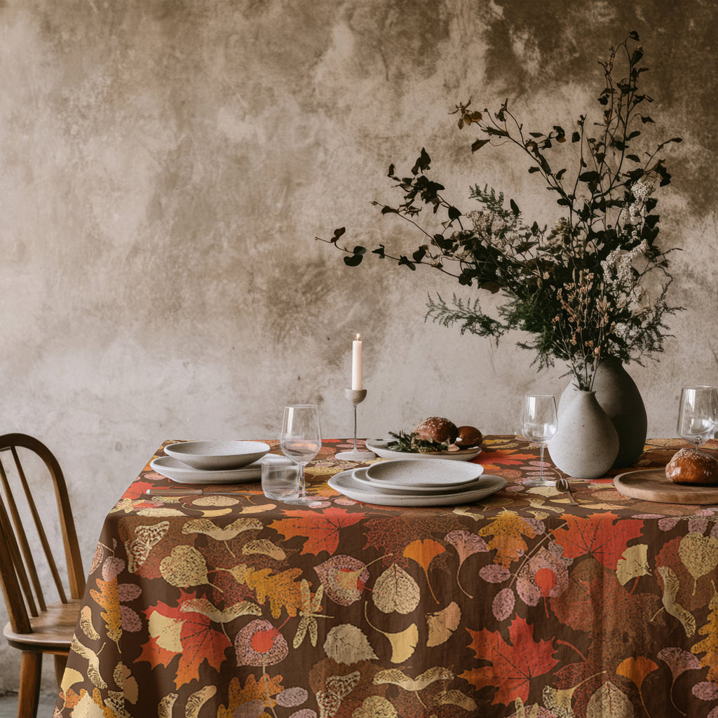 Fall leaves cotton twill tablecloth styled on a dining table with rustic plates, glassware, and autumn decor