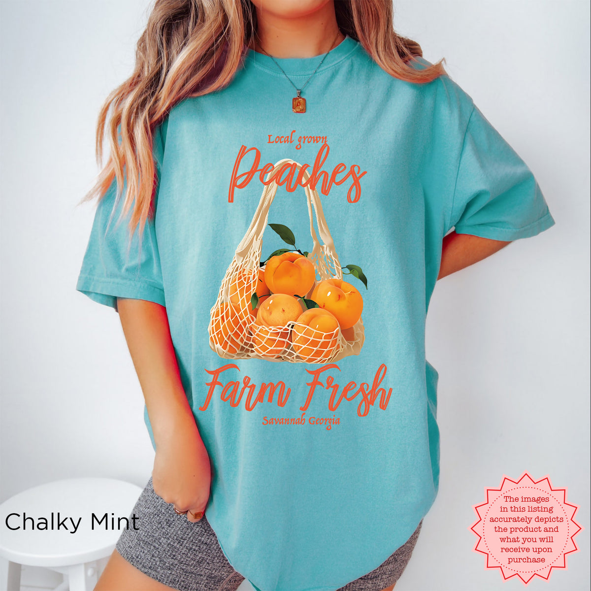 Detailed view of the peach artwork on the Farm Fresh T-shirt, featuring illustrated peaches, leafy green details, and a rustic market-style produce bag.
