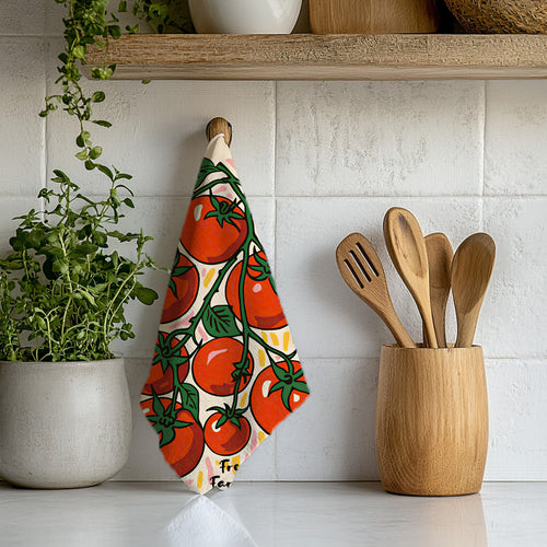 Tea towel draped over an oven handle, showcasing the colorful farmers’ market tomato print.