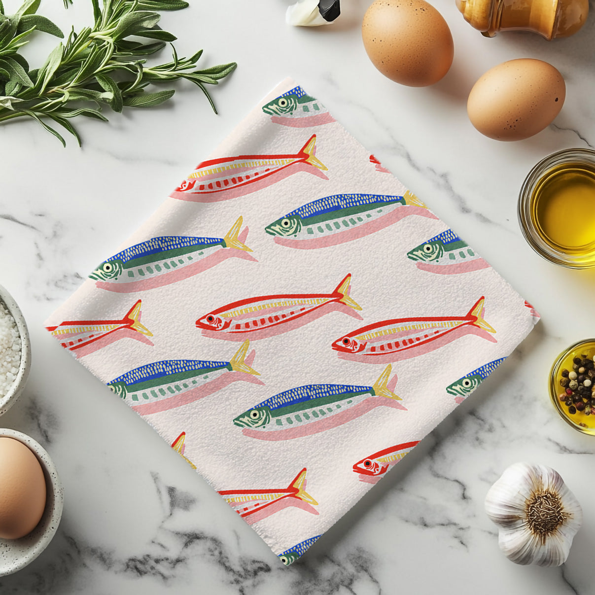 Mediterranean fish pattern tea towel displayed as a stylish coastal kitchen accessory with vibrant blue, green and coral details.